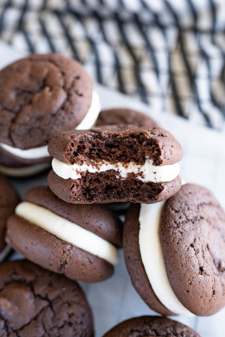 A pile of chocolate whoopie pies. One of the cookies has a bite out of it.