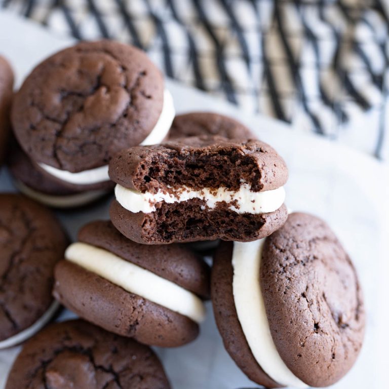 A pile of chocolate whoopie pies. One of the cookies has a bite out of it.