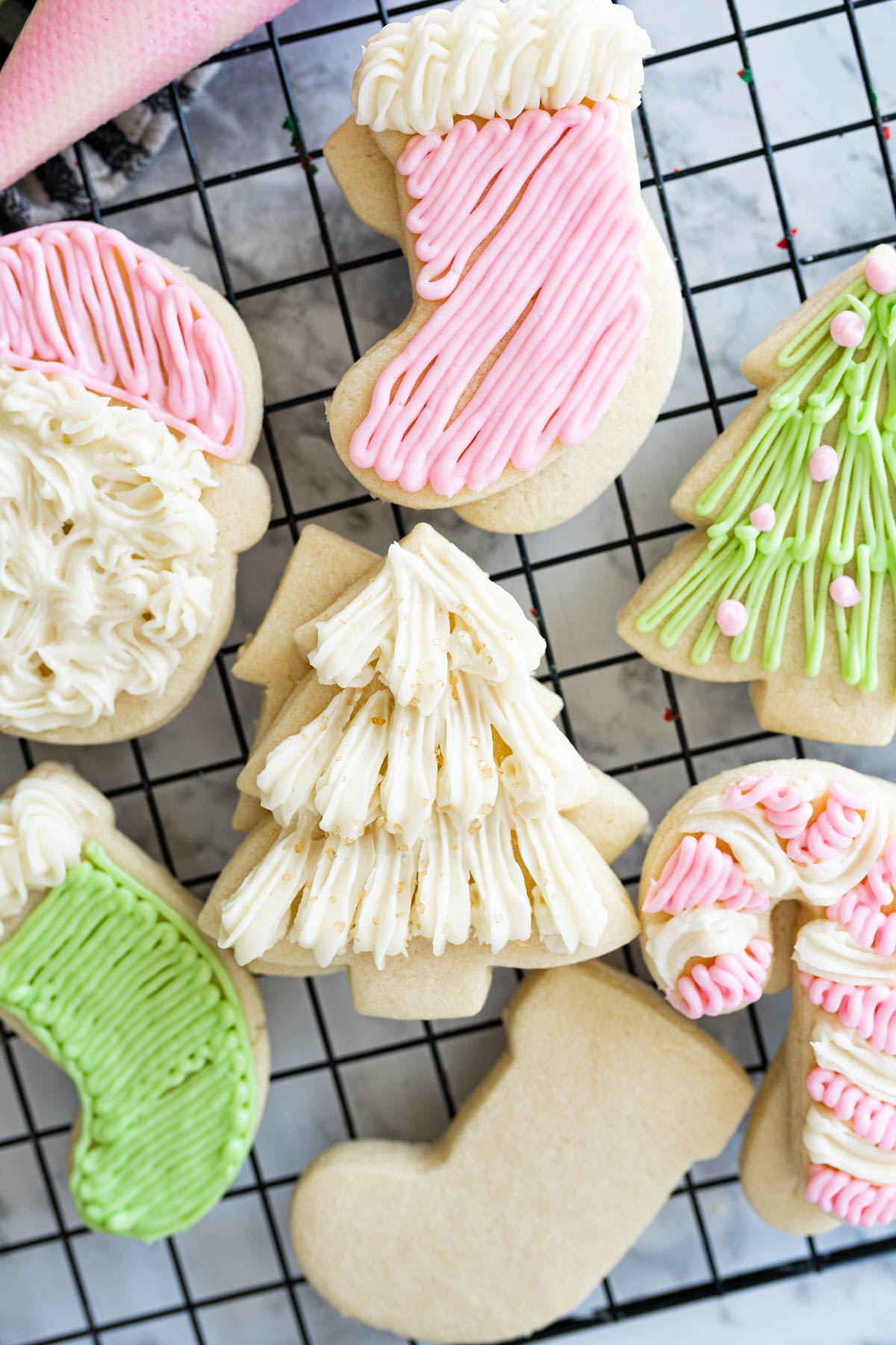Close up of frosted christmas sugar cookies on a wire cooling rack.