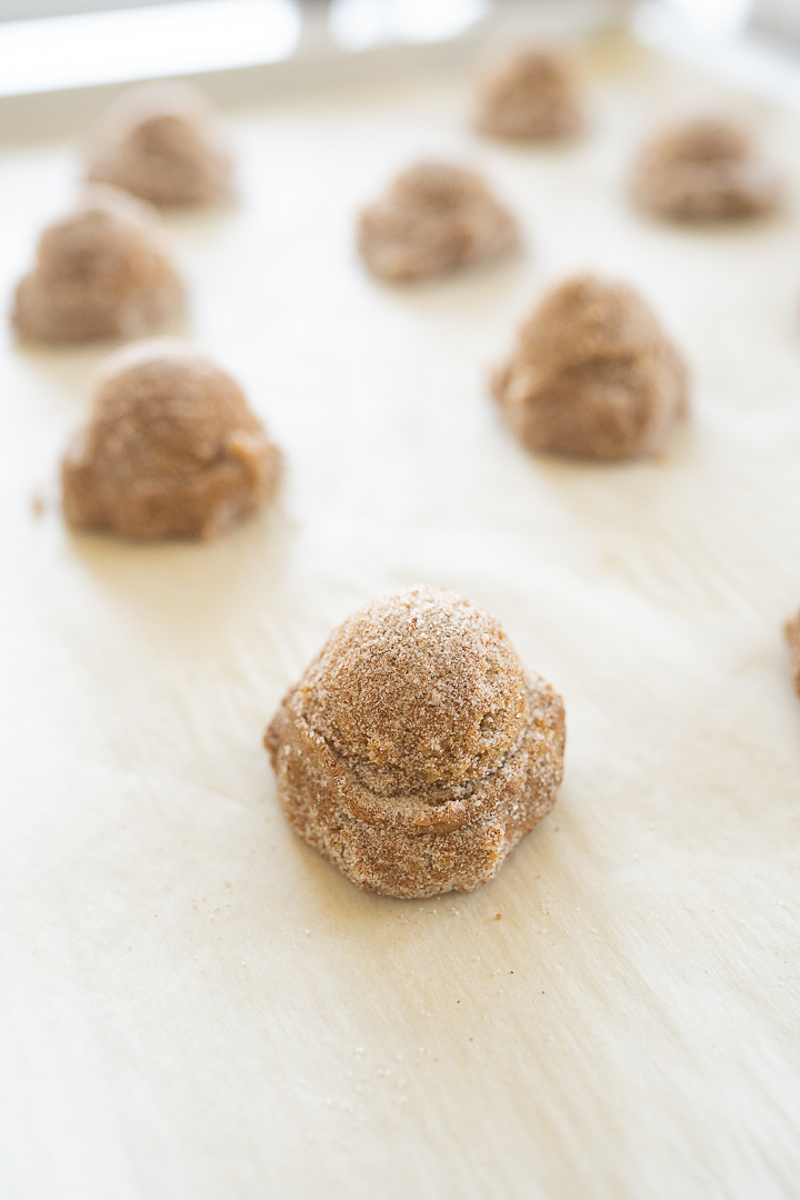Balls of gingerbread cookie dough on a cookie sheet. 