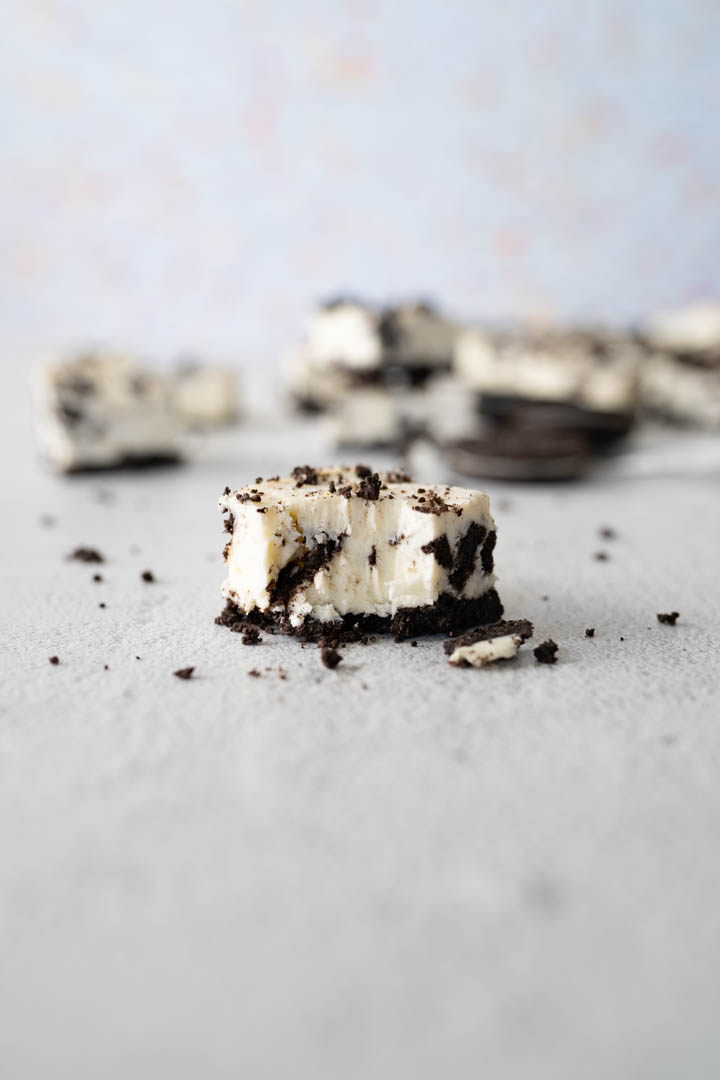 One oreo cheesecake bite in focus on the counter. 