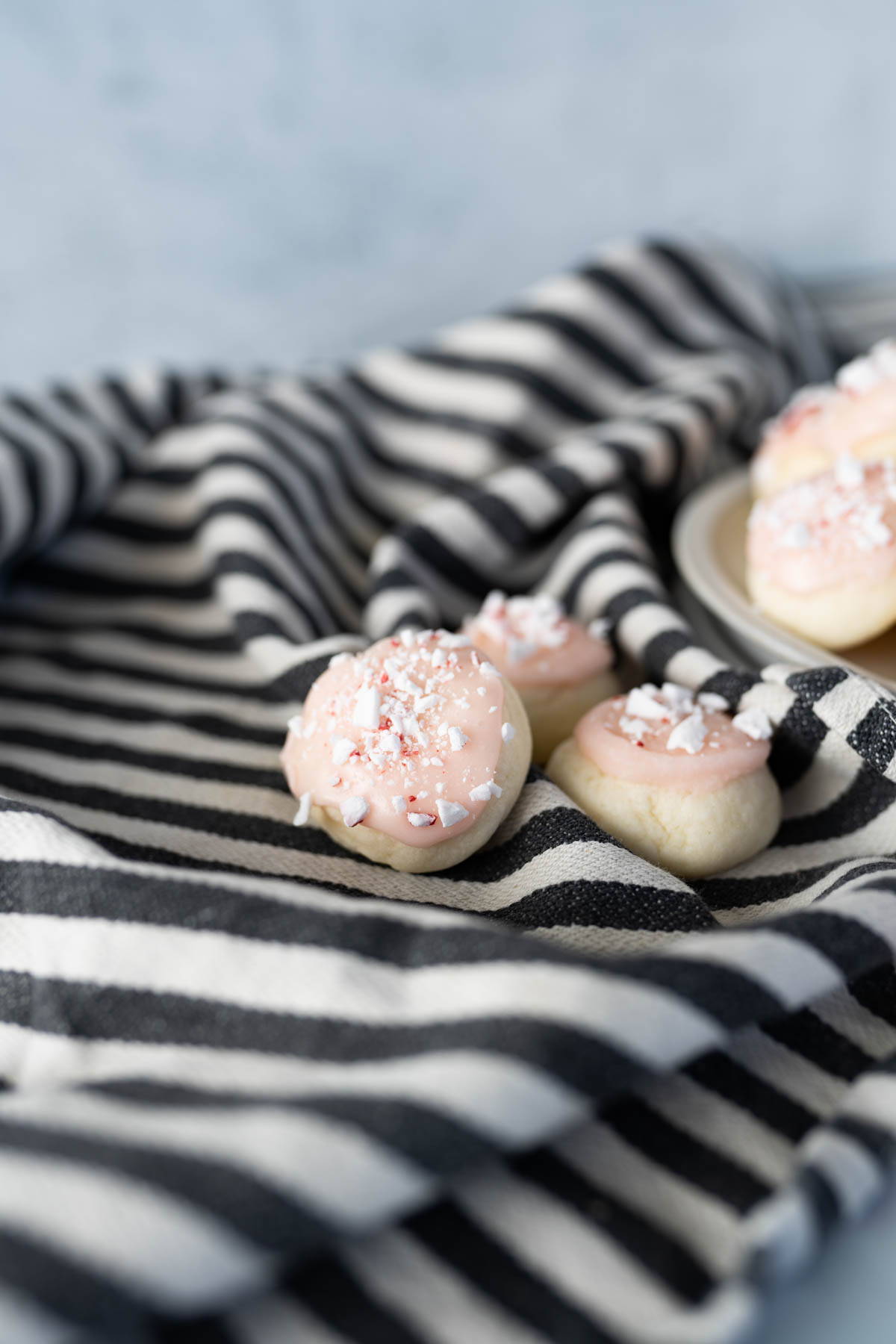 Peppermint frosted meltaway cookies on a striped towel. 