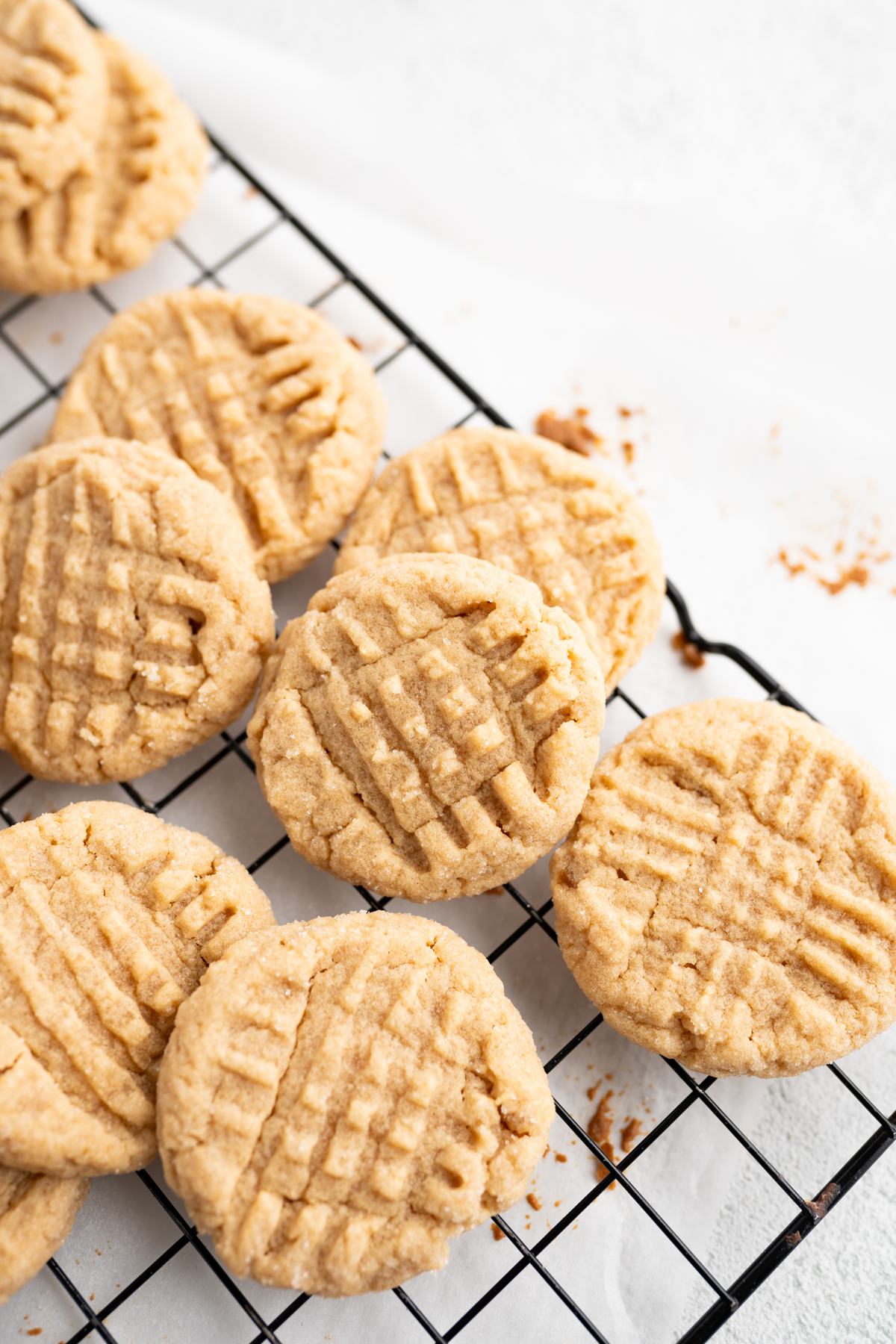 Aerial view of peanut butter cookies scattered on a wire cooling rack. 