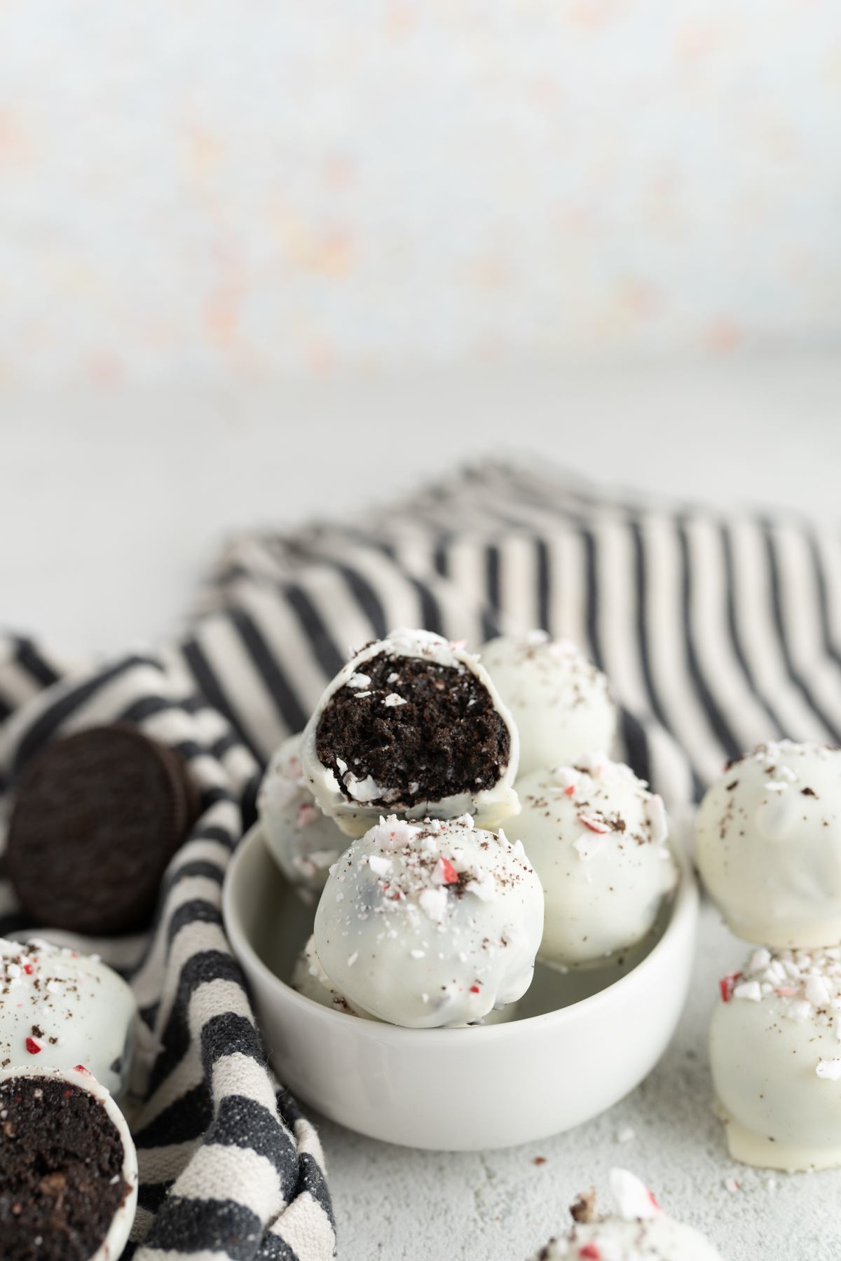 A bowl of peppermint oreo balls, one is cut in half. 