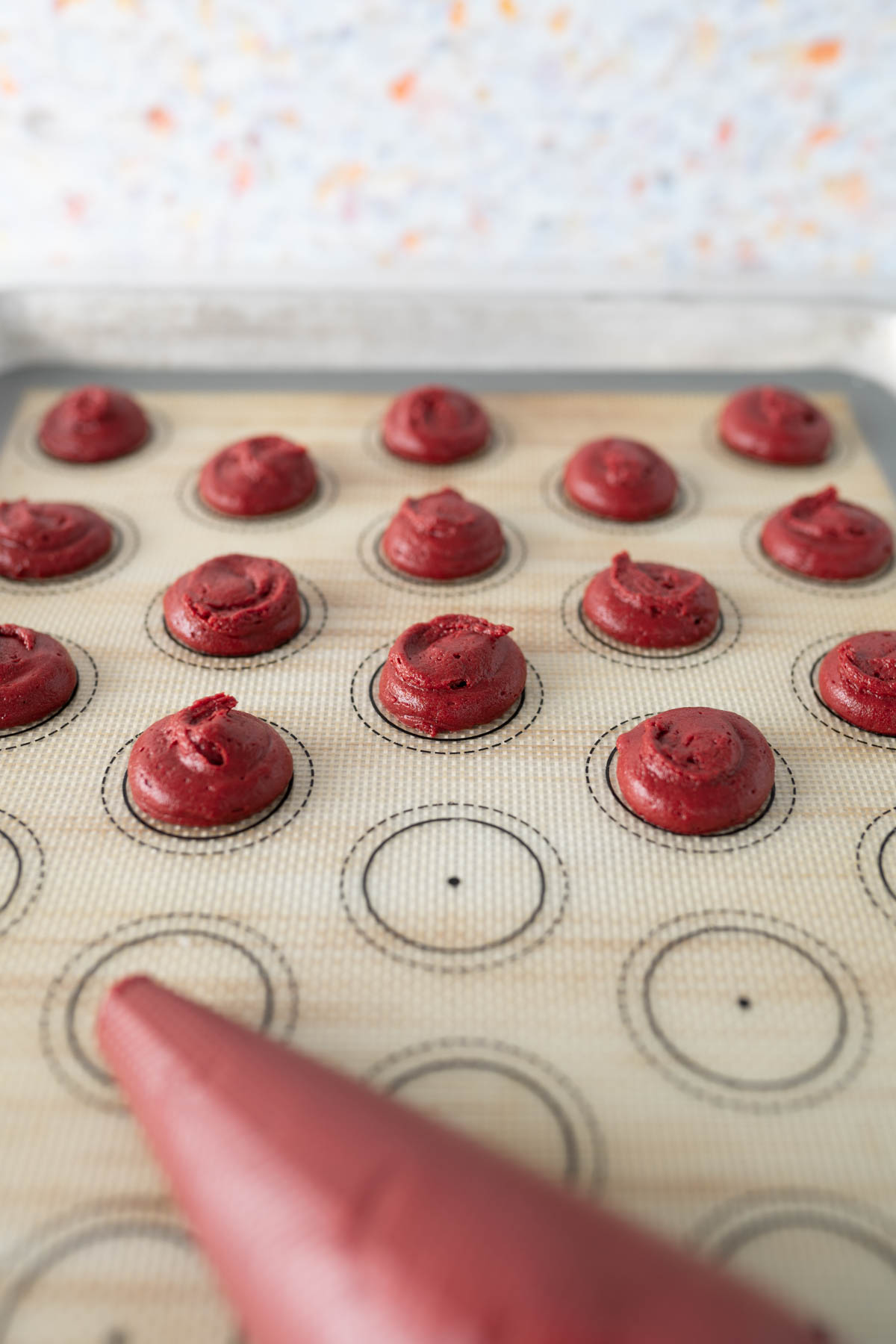 Red velvet whoopie pie dough piped onto a cookie sheet. 