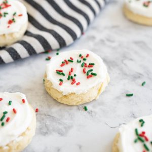 Close up of a soft sugar cookie with white frosting and red and green sprinkles.