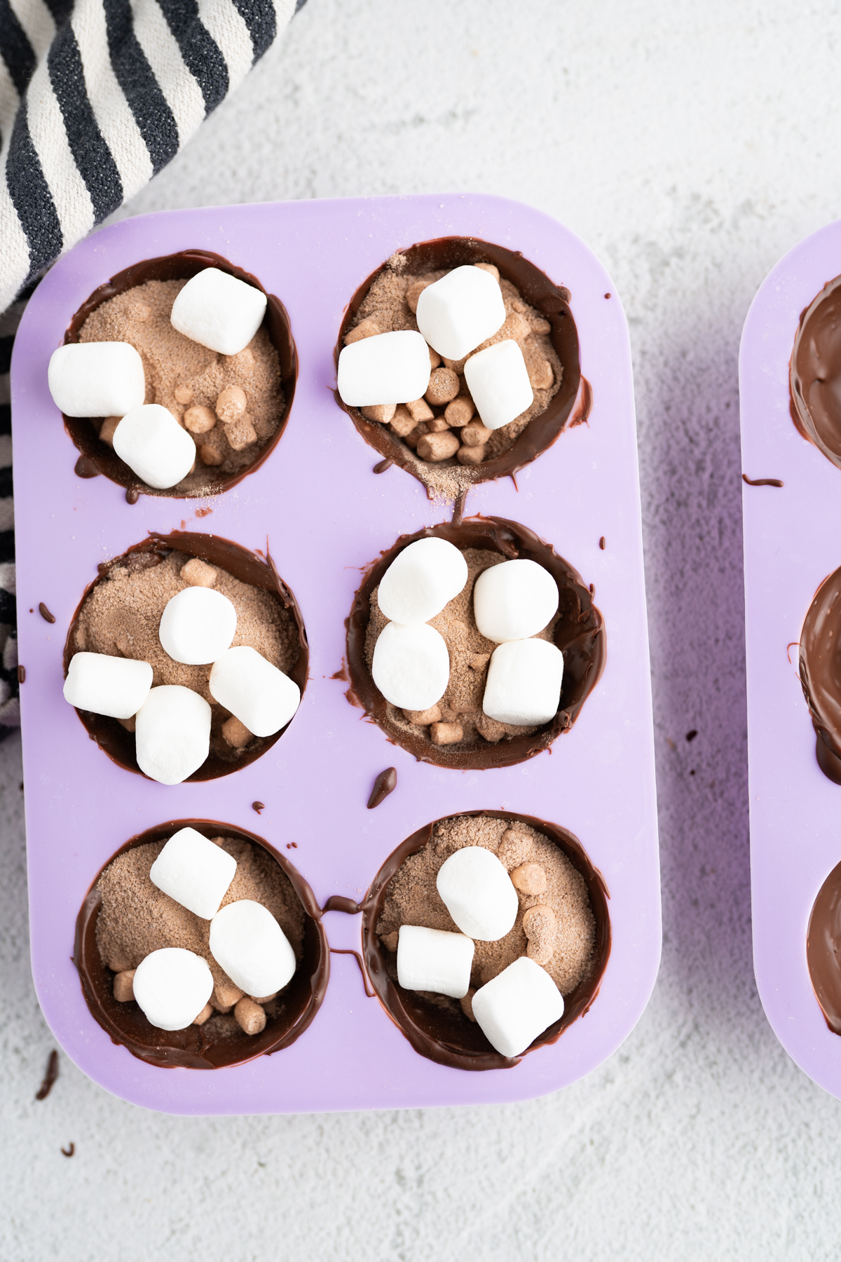 Aerial view of a mold of hot cocoa bombs with hot chocolate powder and mini marshmallows inside. 