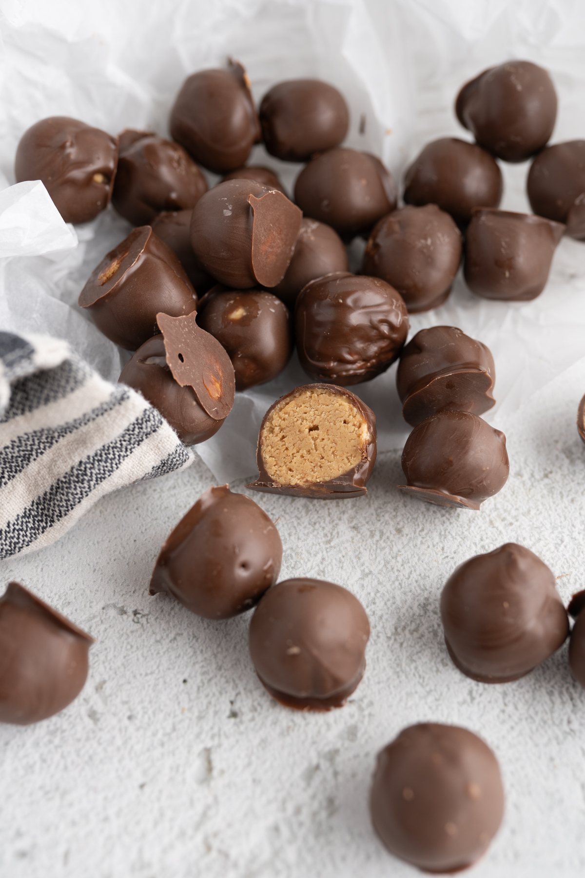 A counter filled with chocolate peanut butter balls - 1 is cut open. 