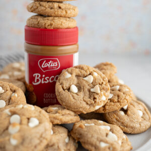 A pile of biscoff cookie butter cookies surrounding a jar of cookie butter.
