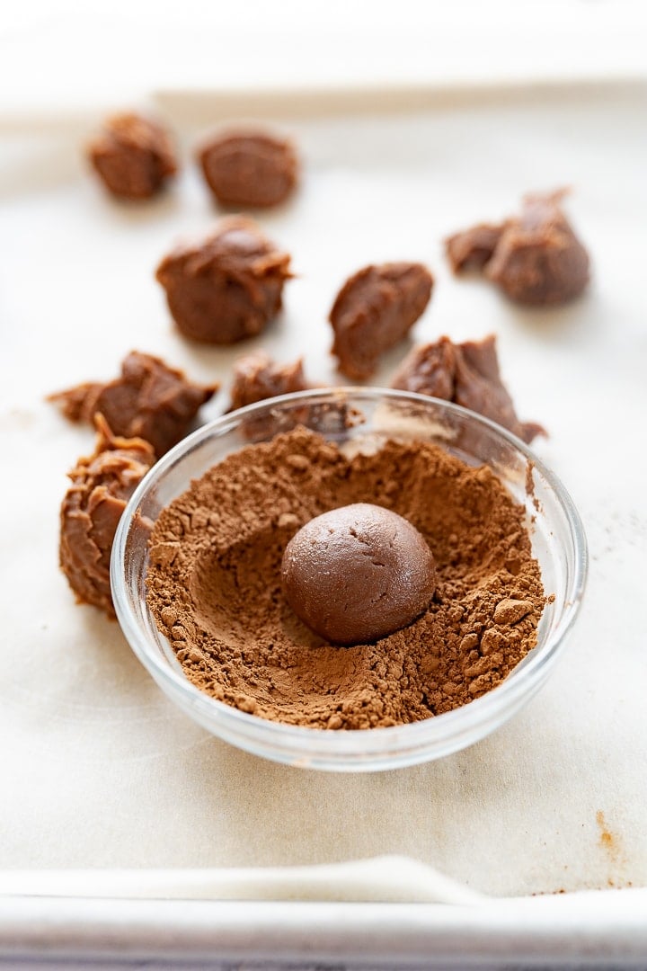 A homemade chocolate truffle being rolled in cocoa powder. 