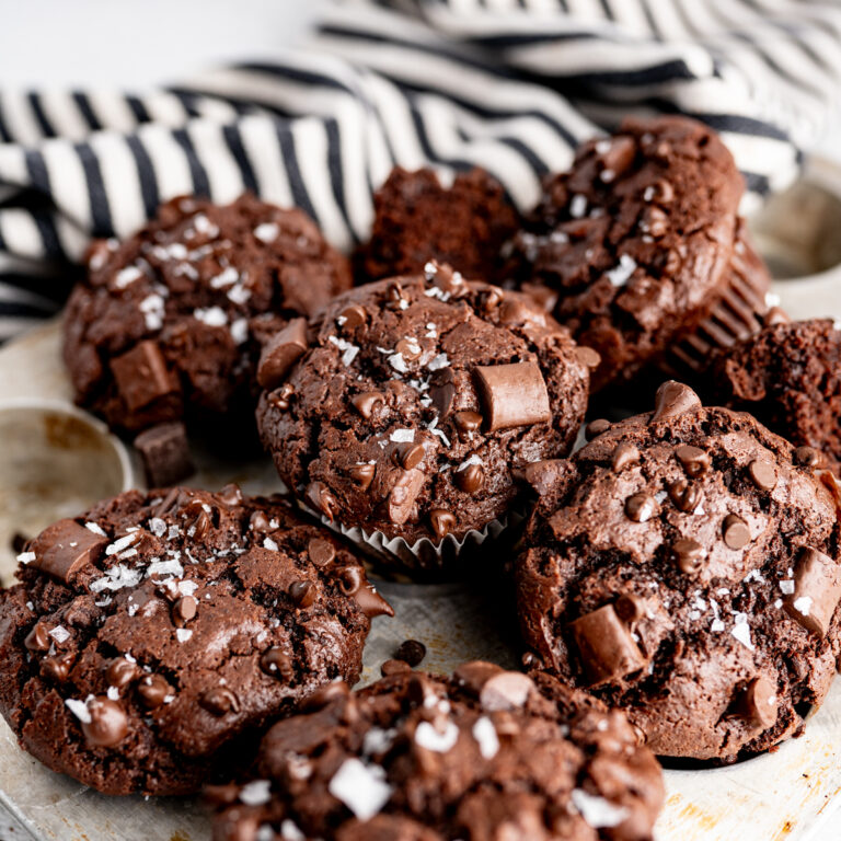 A pile of bakery-style double chocolate muffins. Perfectly moist with an impressive bakery-domed top and THREE types of chocolate chips, these chocolate chocolate chip muffins.