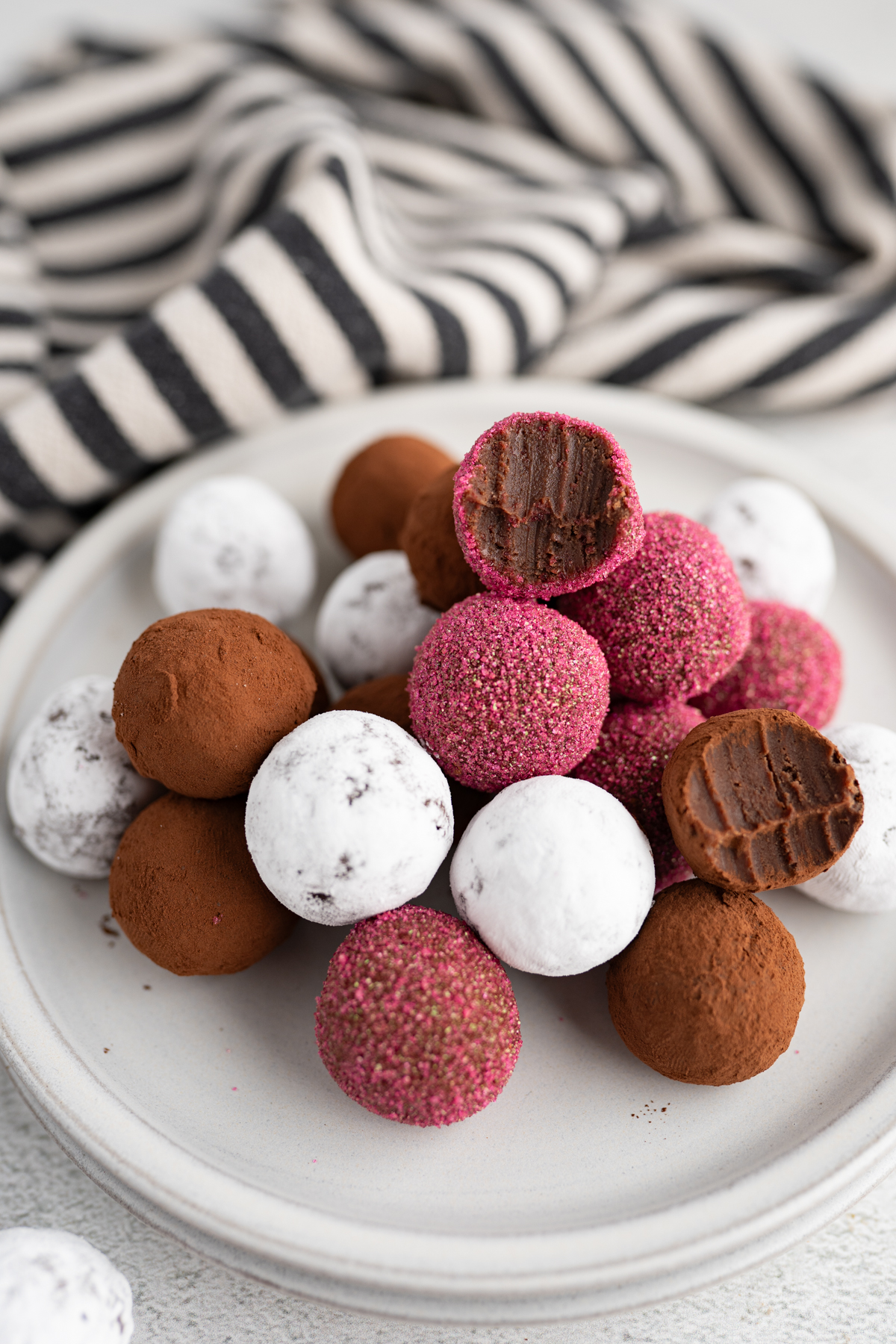 A plate of homemade chocolate truffles with different coatings. 