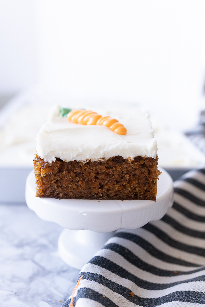 A slice of carrot cake on a tiny cake stand.