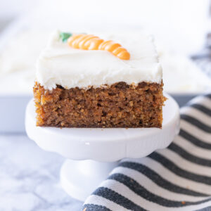 A slice of carrot cake on a tiny cake stand.