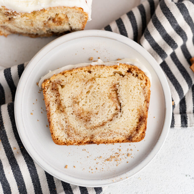 A slice of cinnamon bread with icing on a plate.