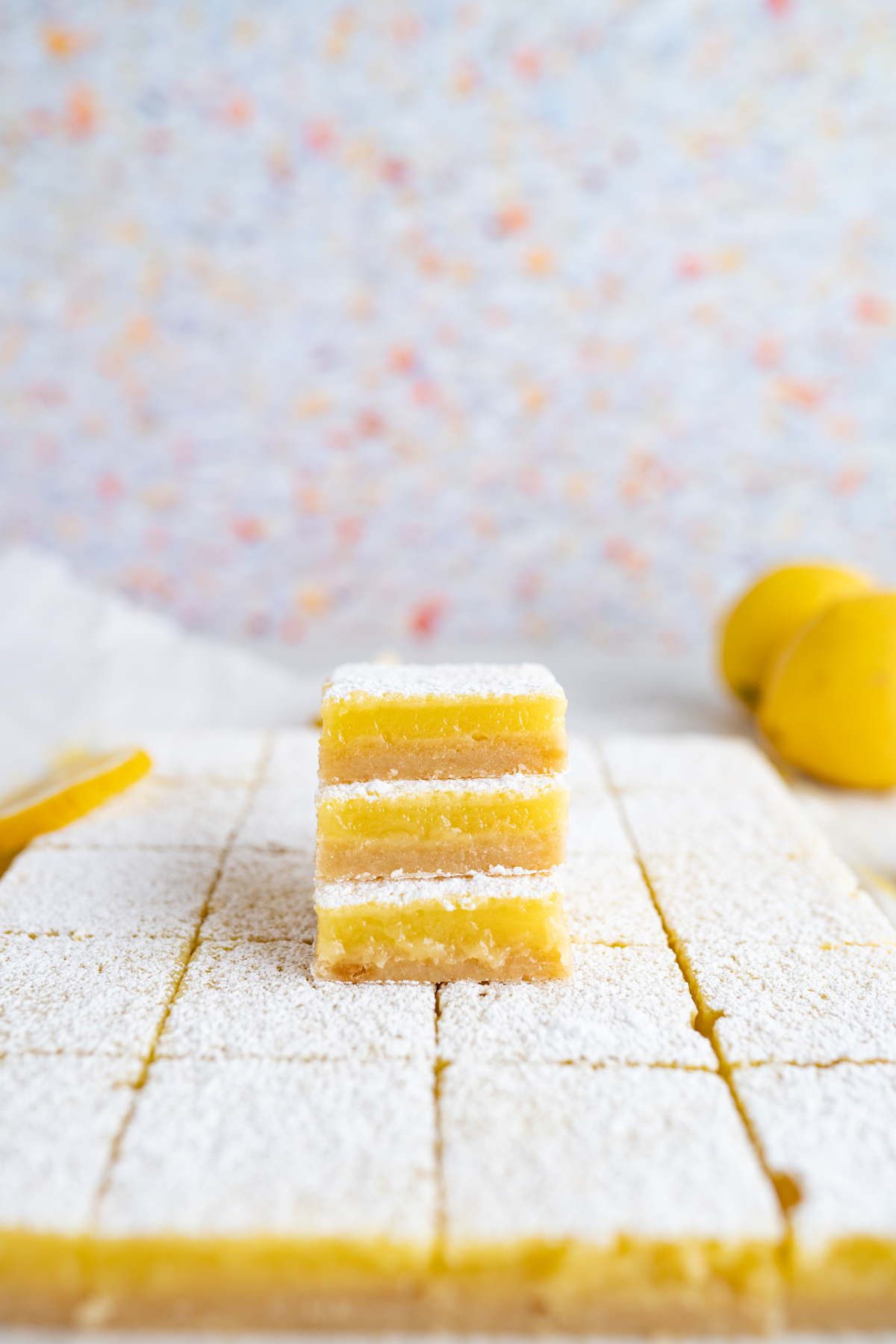 Stack of 3 lemon bars on top of  a grid of additional bars. 