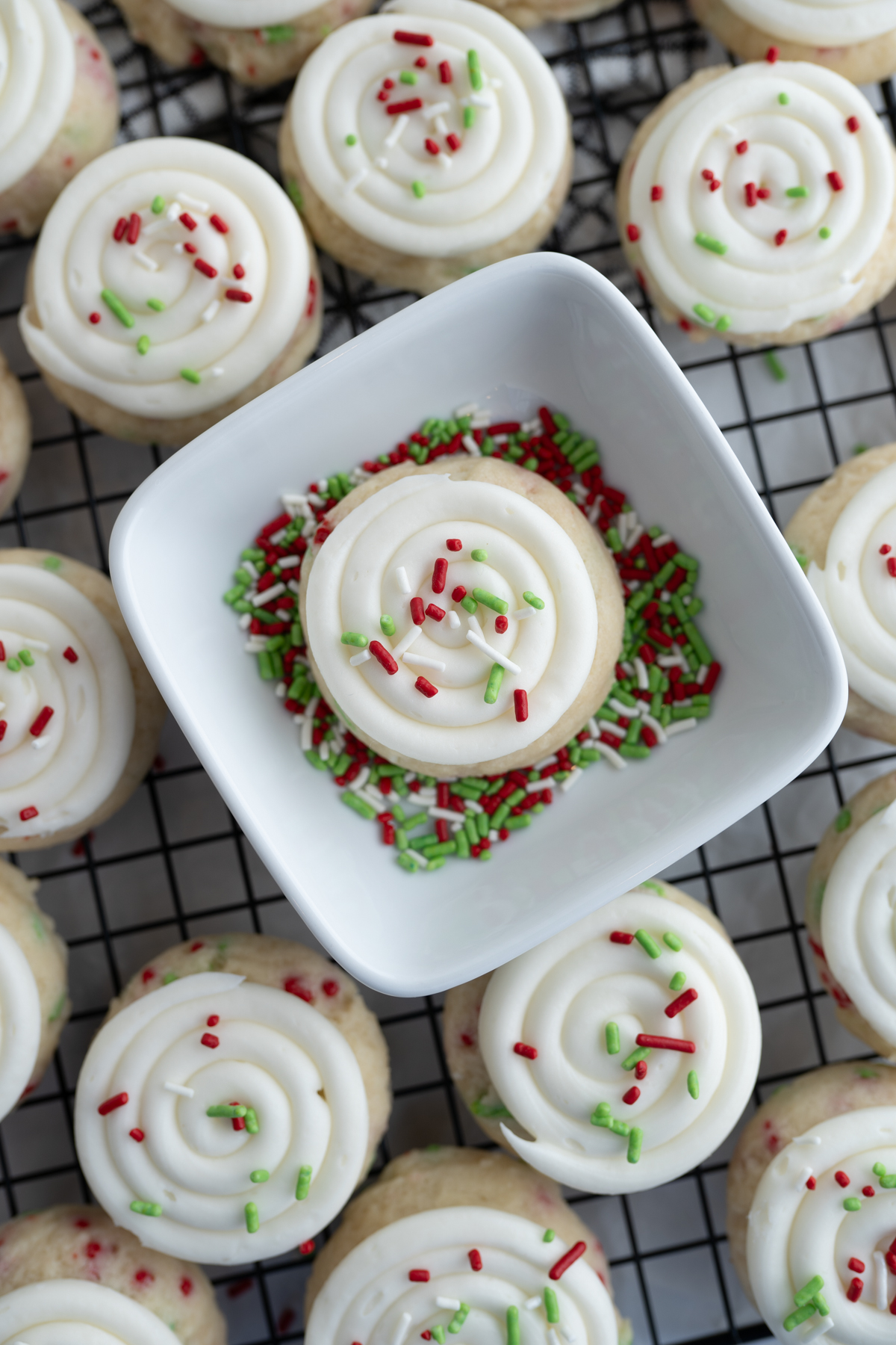 A cake batter cookie in a bowl of christmas sprinkles. 