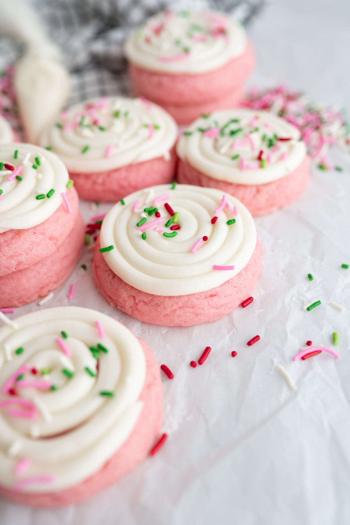 Sprinkles scattered on the counter next to Christmas pink velvet cookies. 