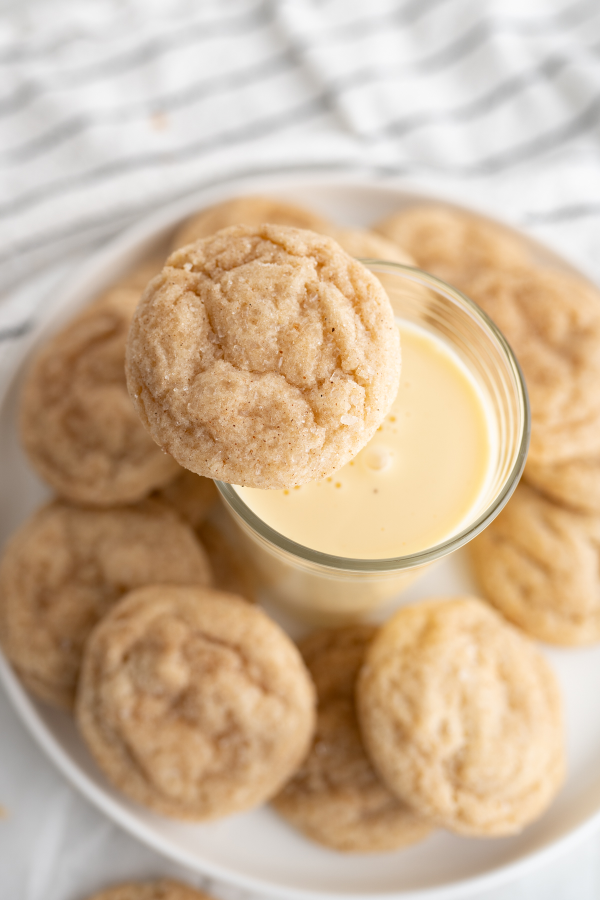 Aerial view of egg nog snickerdoodles on a plate with a glass of egg nog. 