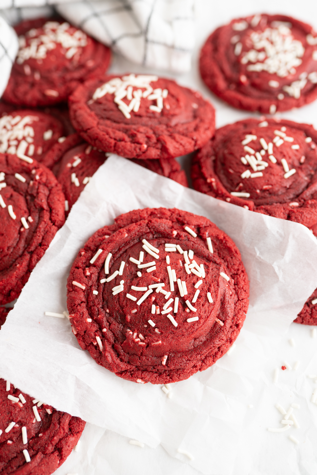 Close up of a red velvet cake mix cookie topped with white sprinkles. 