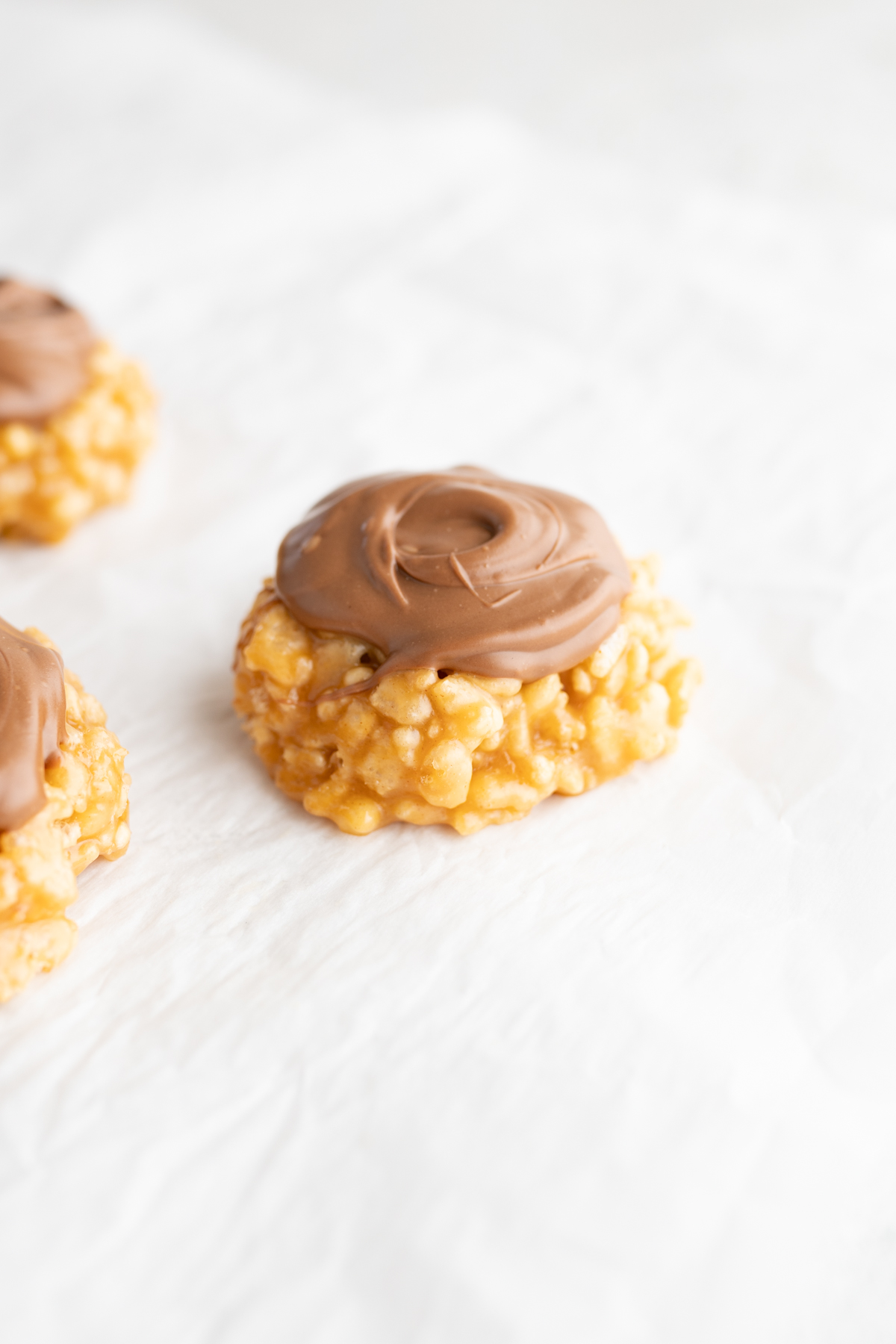 A single scotcharoo shaped like a cookie on a piece of parchment. 