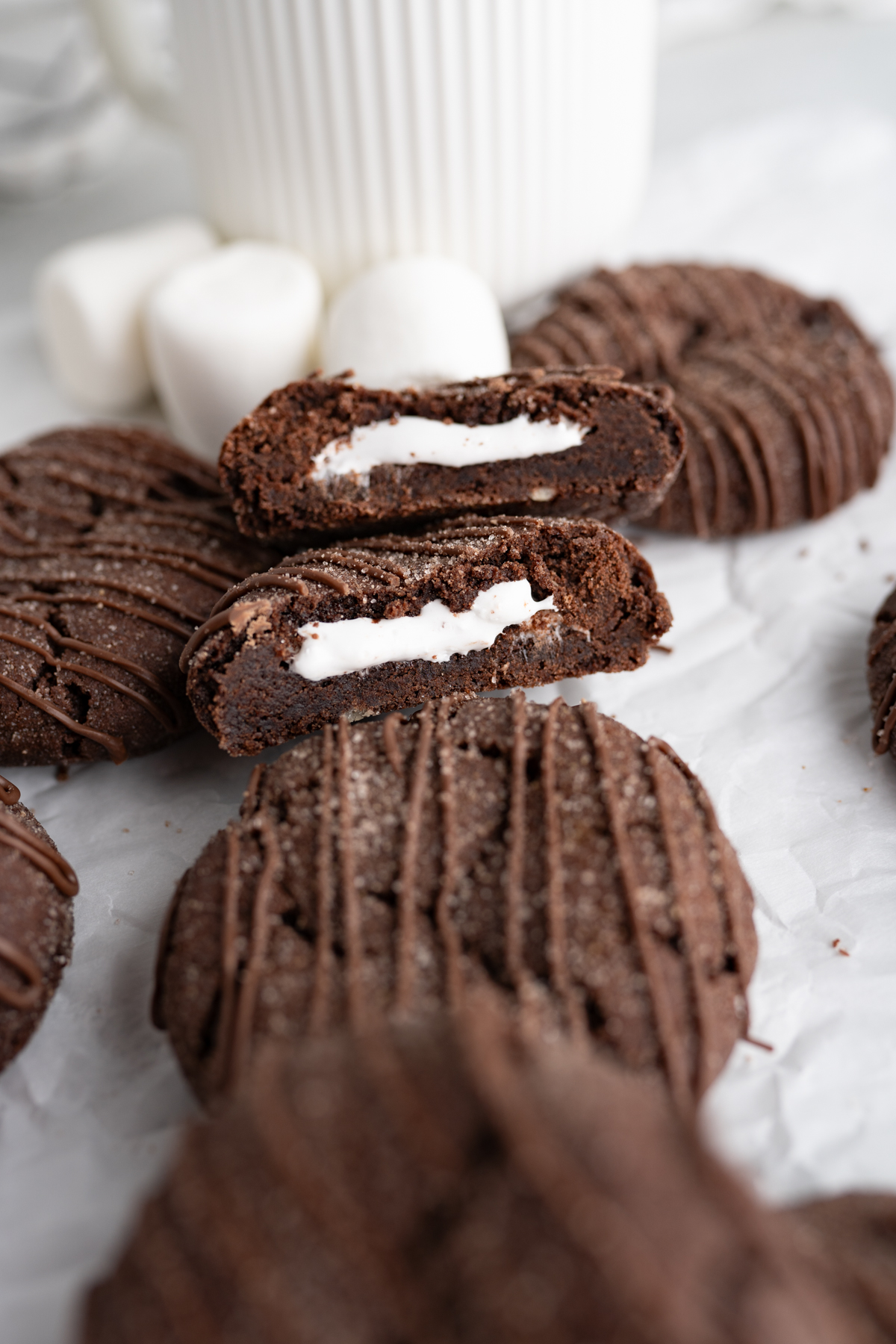Close up of a mini hot cocoa bomb cookie that has been cut in half to show a marshmallow. 