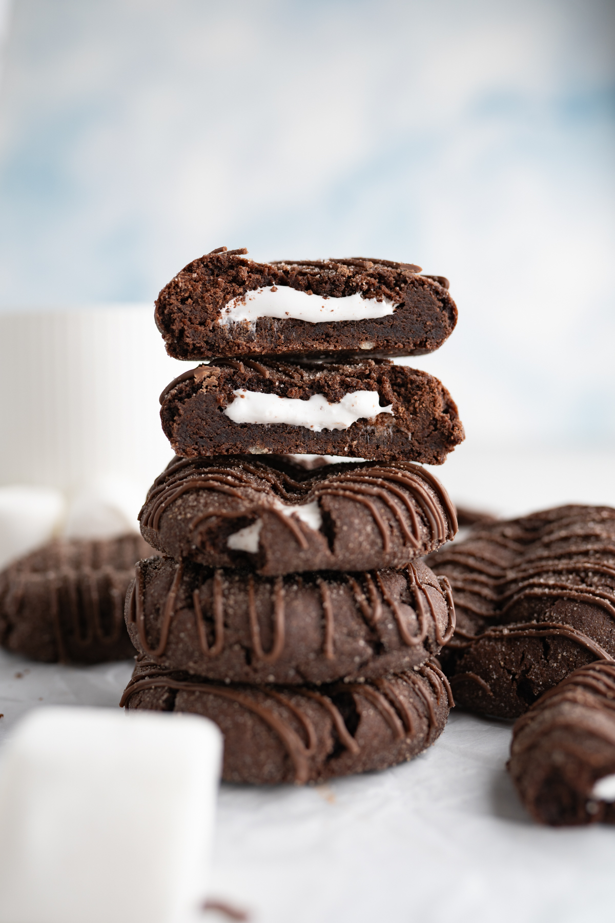 A stack of small hot cocoa bomb cookies cut in half to reveal a marshmallow inside. 