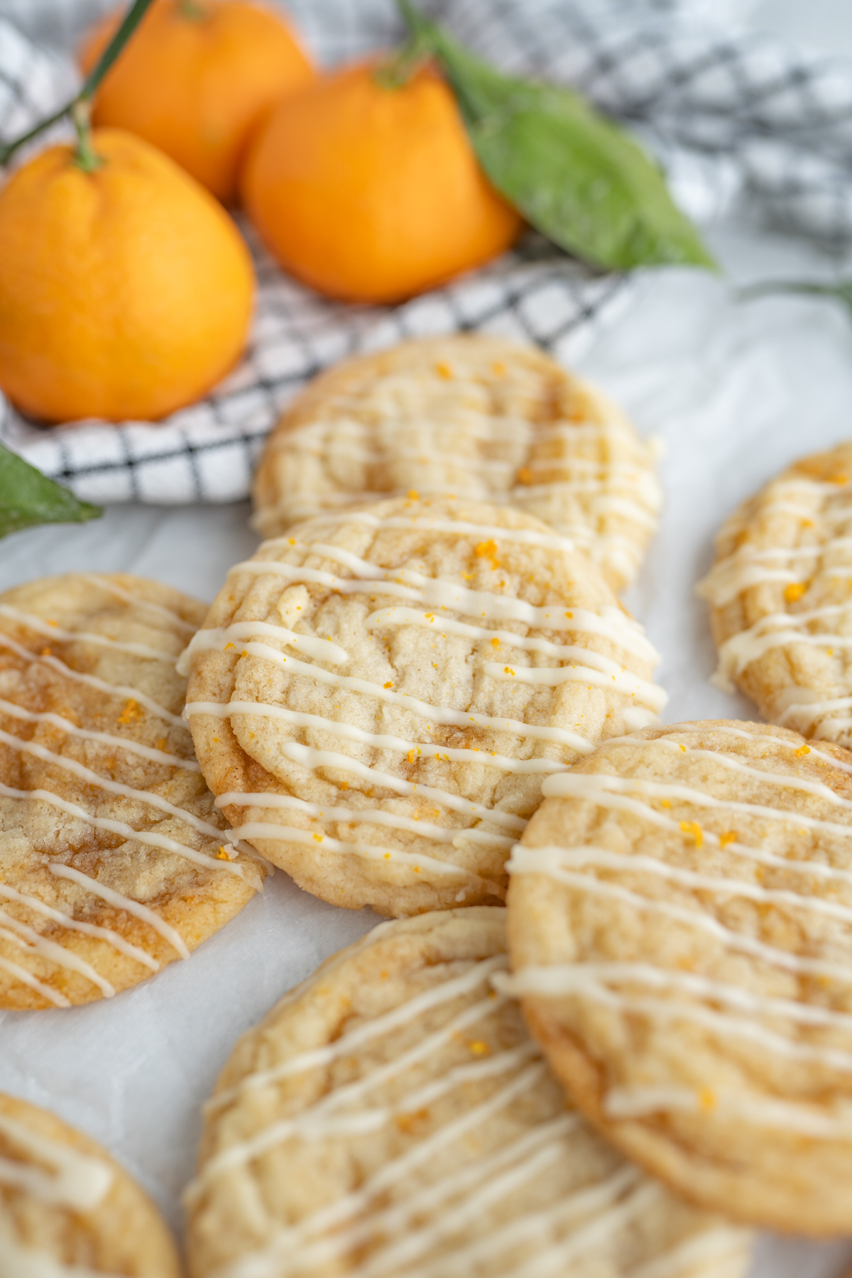 Orange sweet roll cookie in a pile next to fresh oranges. 