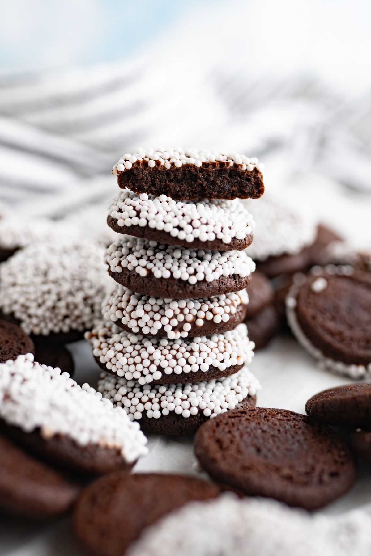 A stack of chocolate cookies covered in white sprinkles. 