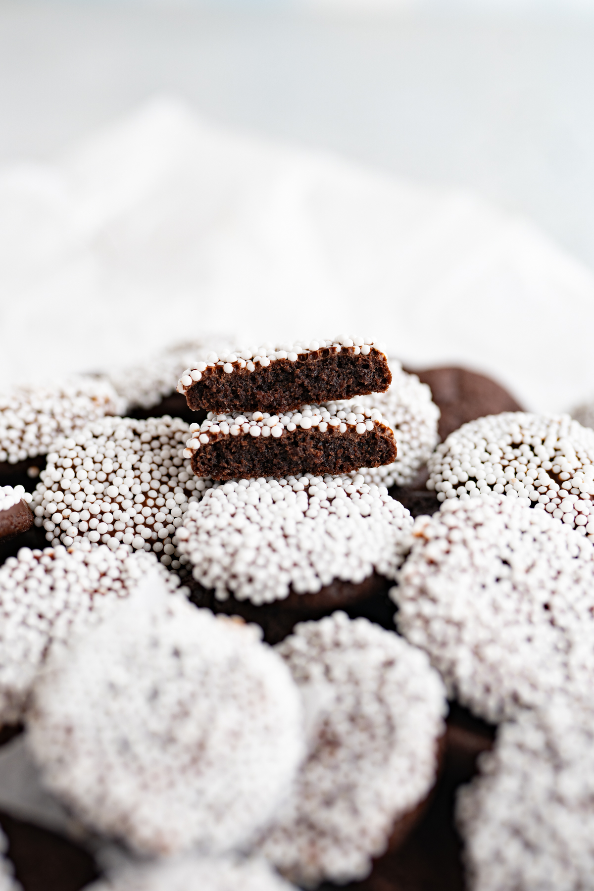 Close up of a snocap candy-inspired cookie cut in half to reveal a soft chocolate cookie. 