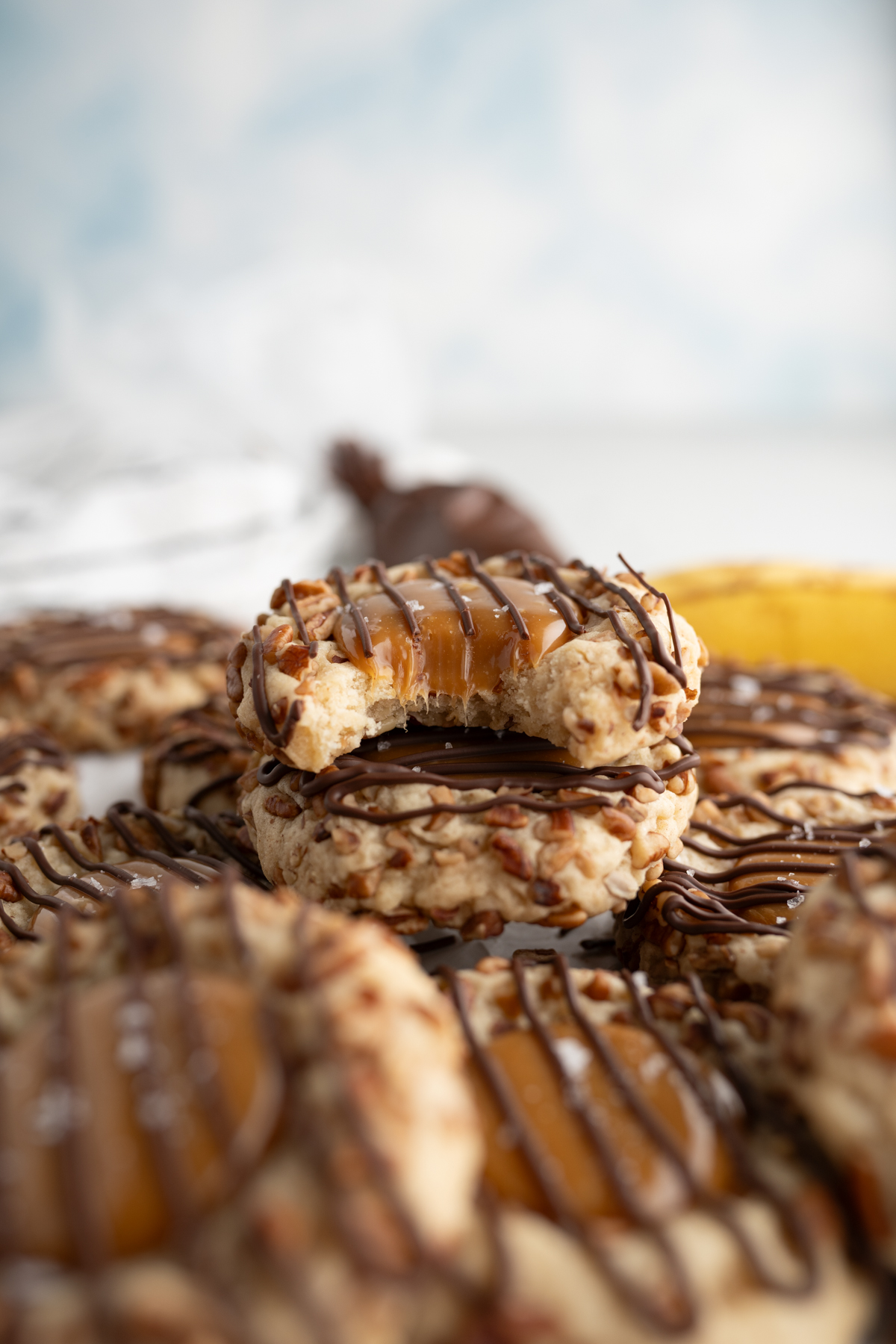 A banana turtle cookie with a bite taken out of it sitting on a pile of other cookies. 