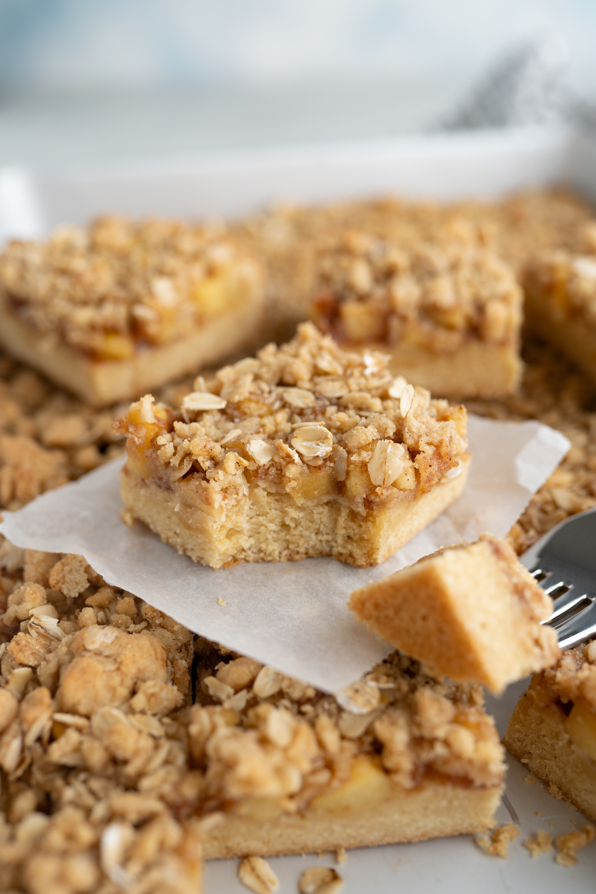 an apple crumb cookie bar cut into a square with a forkful taken out of it. 