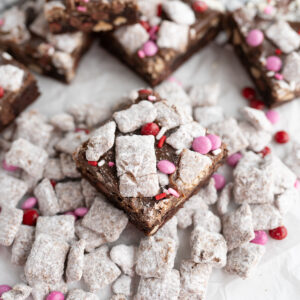 A puppy love cookie bar - chocolate crinkle cookie with m&ms, peanut butter chips, ganache, puppy chow.