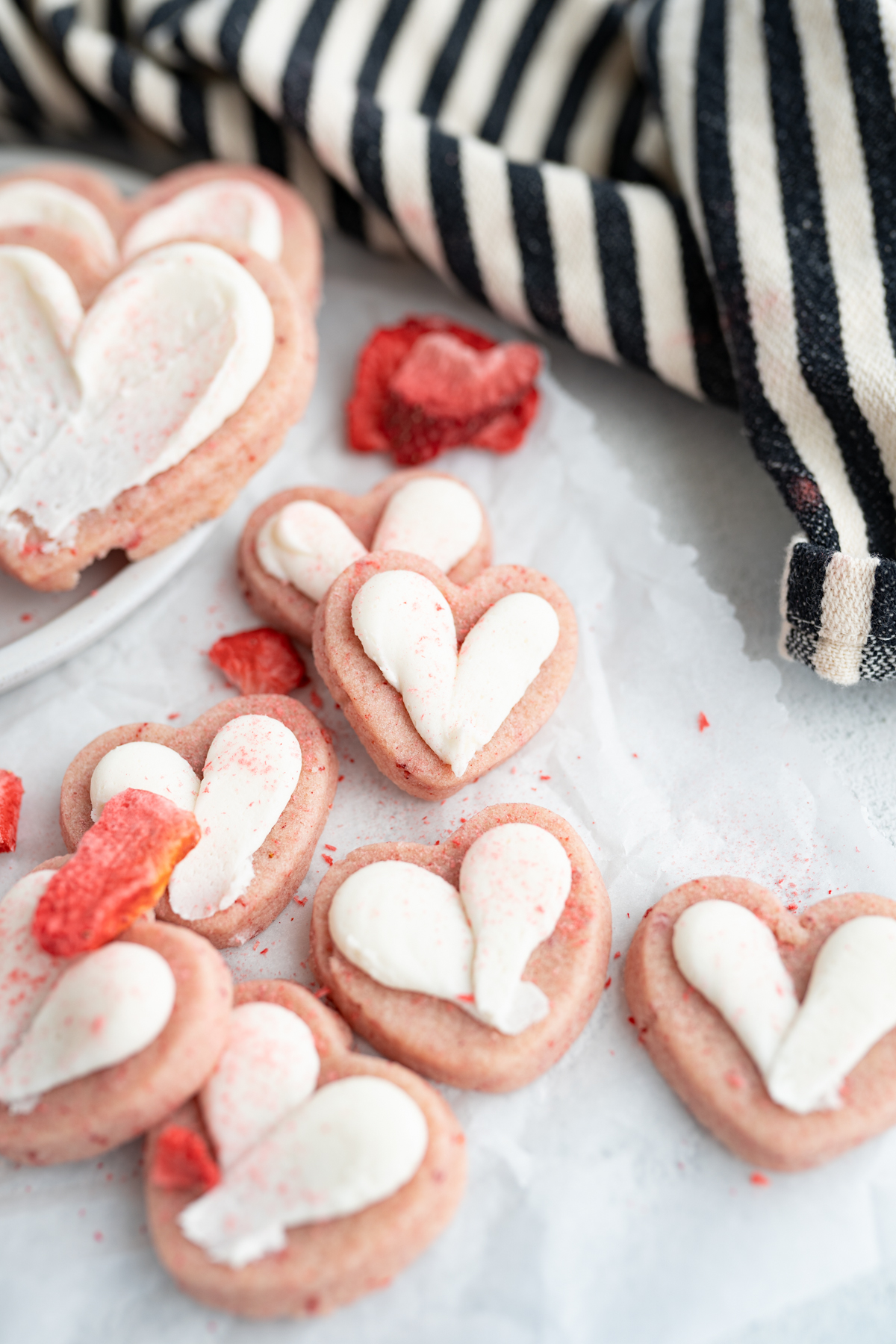 Small heart-shaped strawberry cookie topped with frosting. 