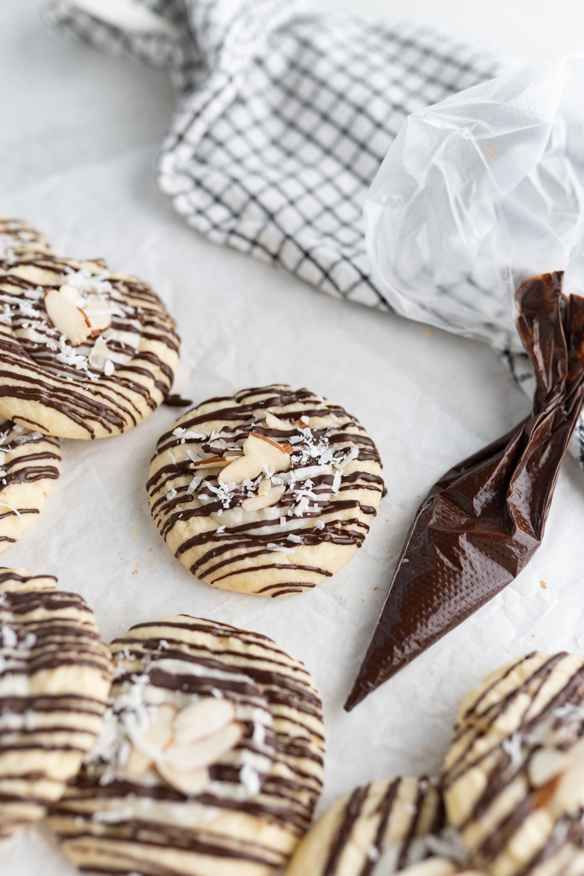 Aerial view of coconut almond joy cookies next to a piping bag of chocolate. 