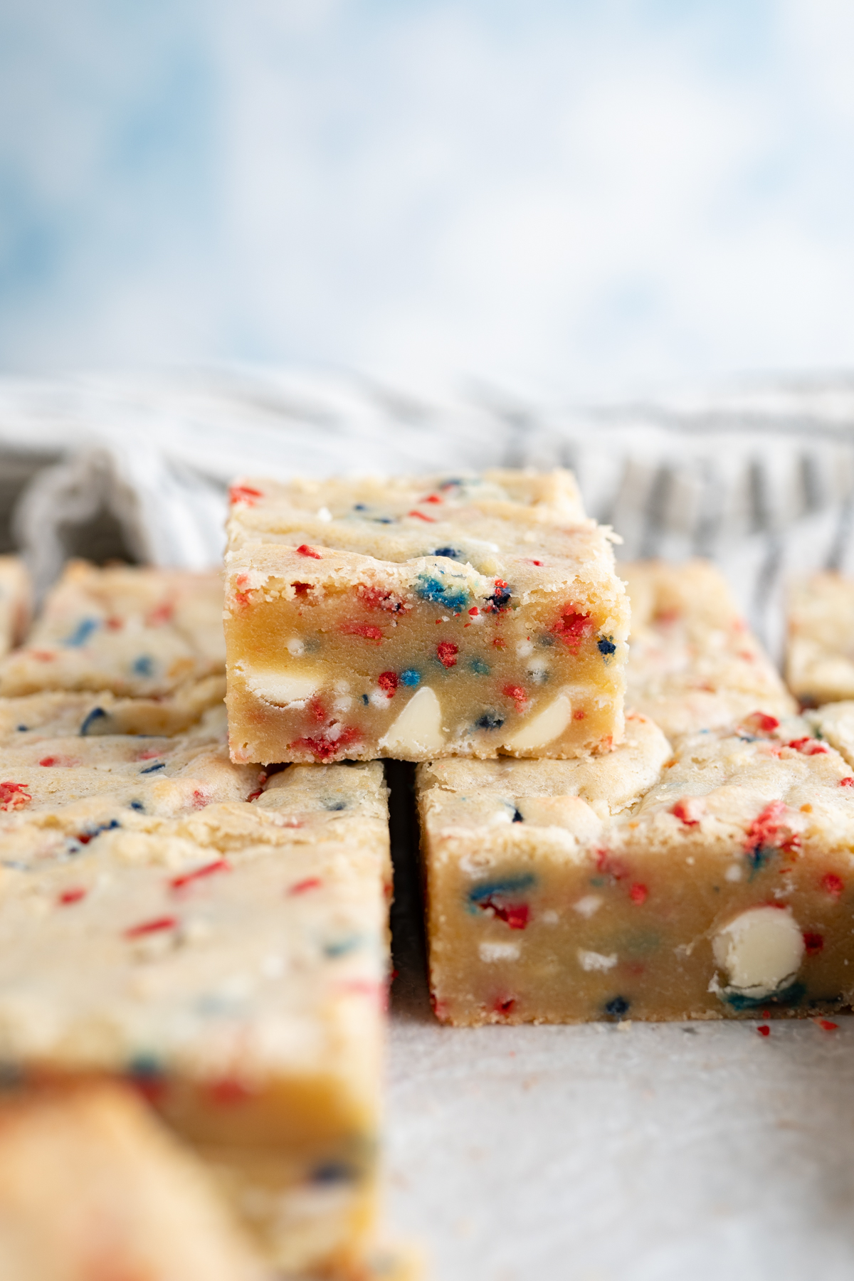 A cake batter blondie stacked on other blondies with red, white, blue sprinkles. 